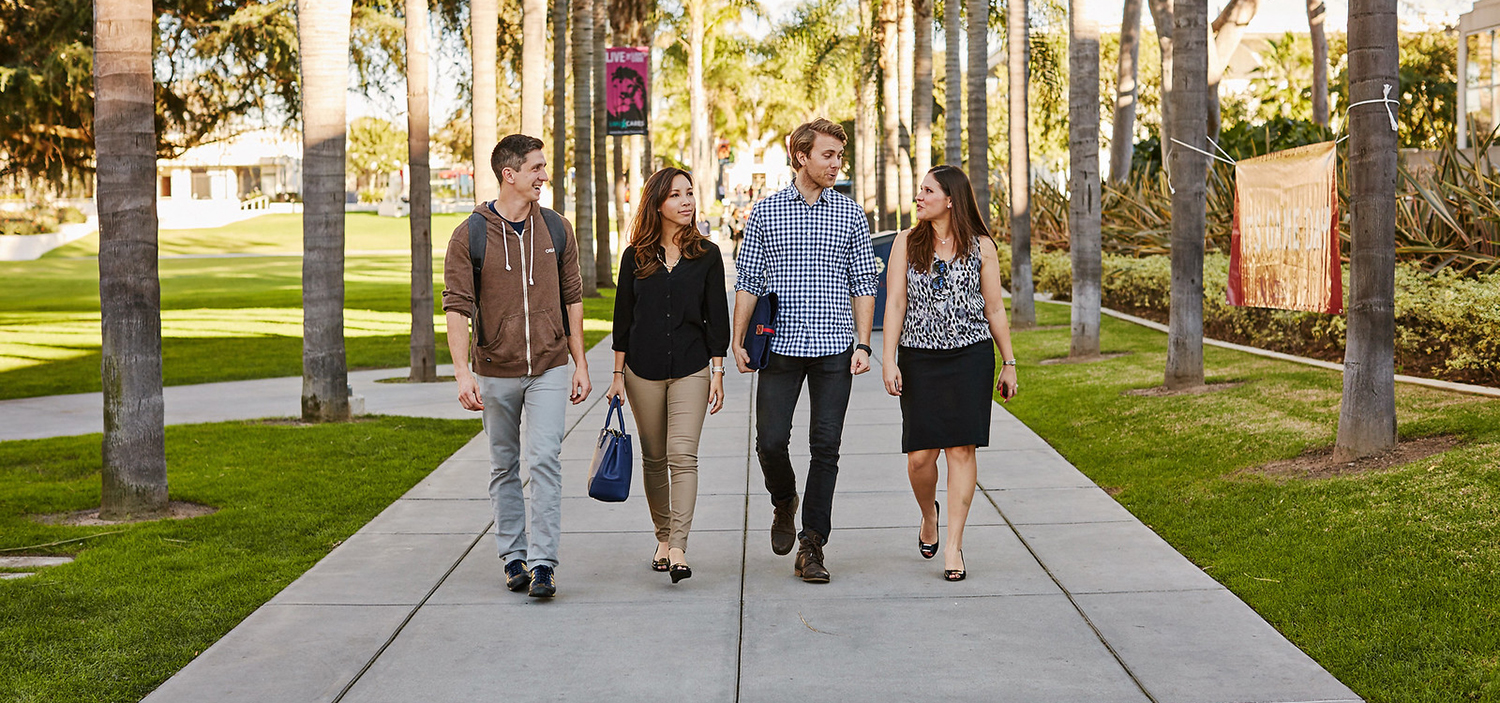 Four MBA students walking down a sidewalk on the LMU campus